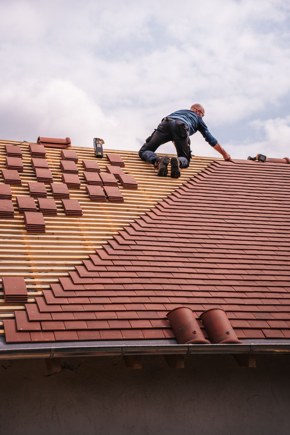 Roofer installing tiles on a pitched roof